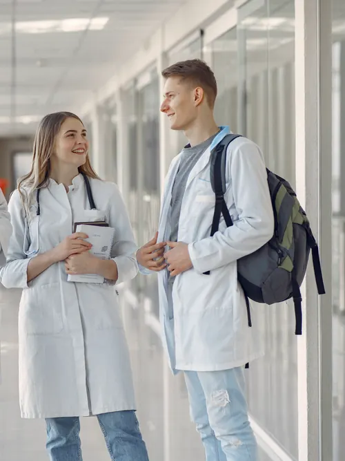 Medizinstudierende im weißen Kittel im Gespräch auf dem Klinikflur