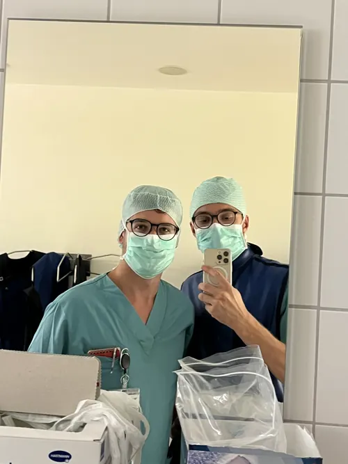 Zwei Medizinstudenten in OP-Kleidung mit Haube und Mundschutz